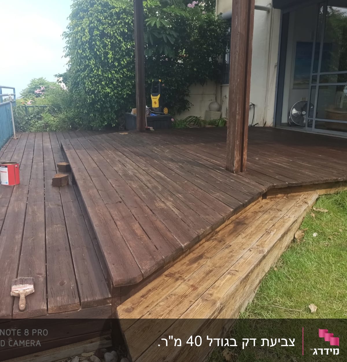 מרפסת עץ עם פח צבע ומברשת על הרצפה